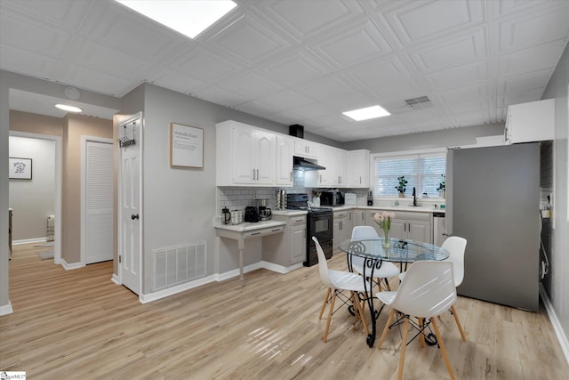 kitchen featuring sink, black electric range, decorative backsplash, light hardwood / wood-style floors, and white cabinetry