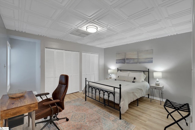 bedroom featuring two closets and light hardwood / wood-style flooring