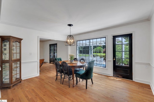 dining area with light hardwood / wood-style flooring, a notable chandelier, and crown molding