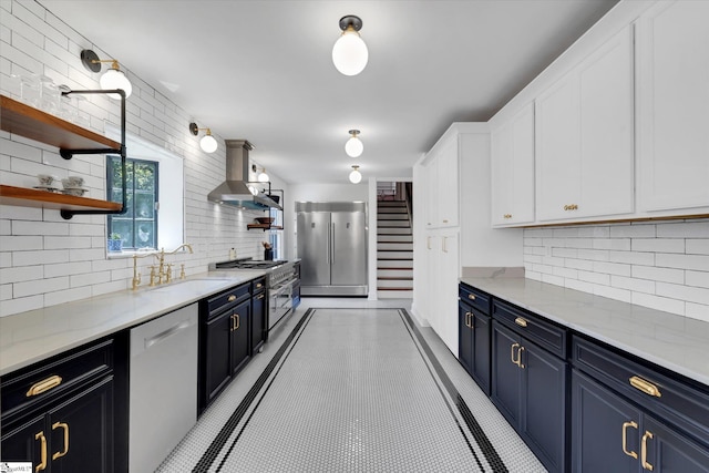 kitchen with white cabinetry, sink, stainless steel appliances, wall chimney range hood, and tasteful backsplash