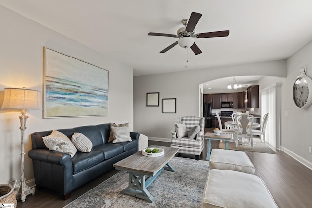 living room featuring ceiling fan with notable chandelier and dark hardwood / wood-style floors