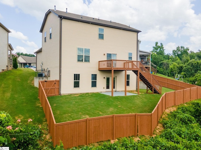 rear view of property featuring a deck, a patio area, and a lawn