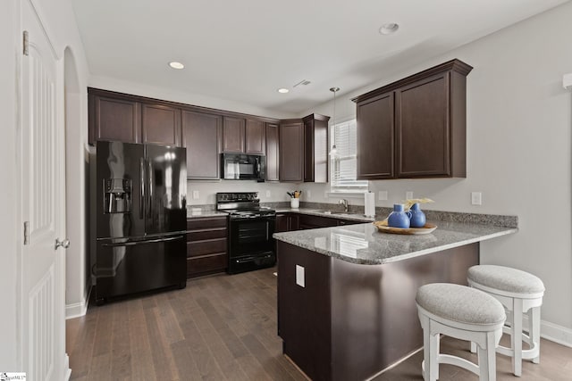 kitchen featuring kitchen peninsula, sink, black appliances, pendant lighting, and dark hardwood / wood-style floors