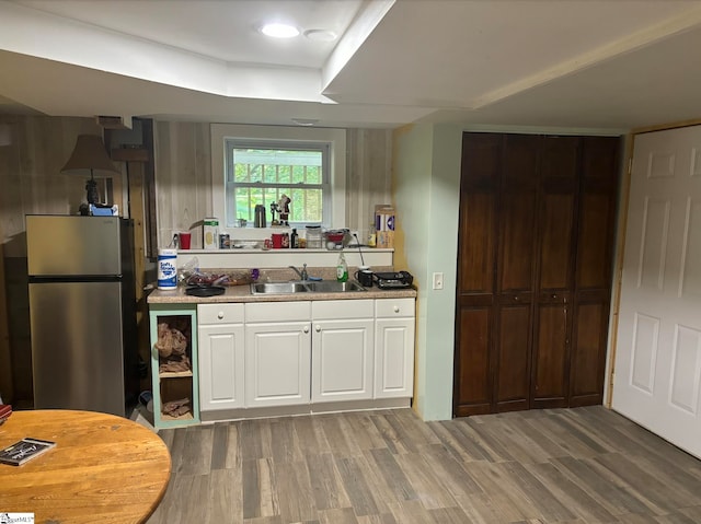 kitchen with sink, white cabinetry, dark hardwood / wood-style flooring, and stainless steel fridge