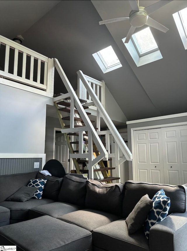 living room featuring a skylight, ceiling fan, and a towering ceiling