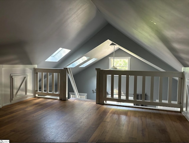 additional living space with lofted ceiling with skylight and dark wood-type flooring