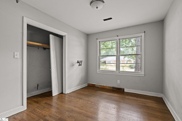 unfurnished bedroom featuring a closet and dark wood-type flooring