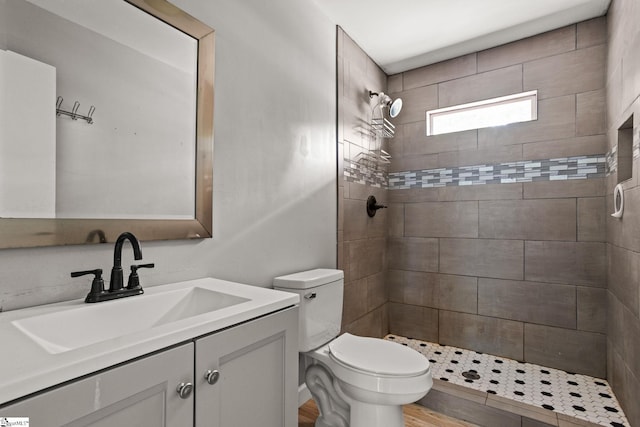 bathroom featuring vanity, toilet, and a tile shower