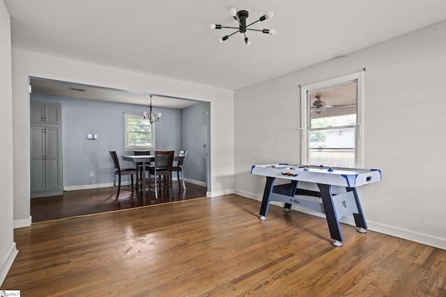 recreation room with dark wood-type flooring and an inviting chandelier