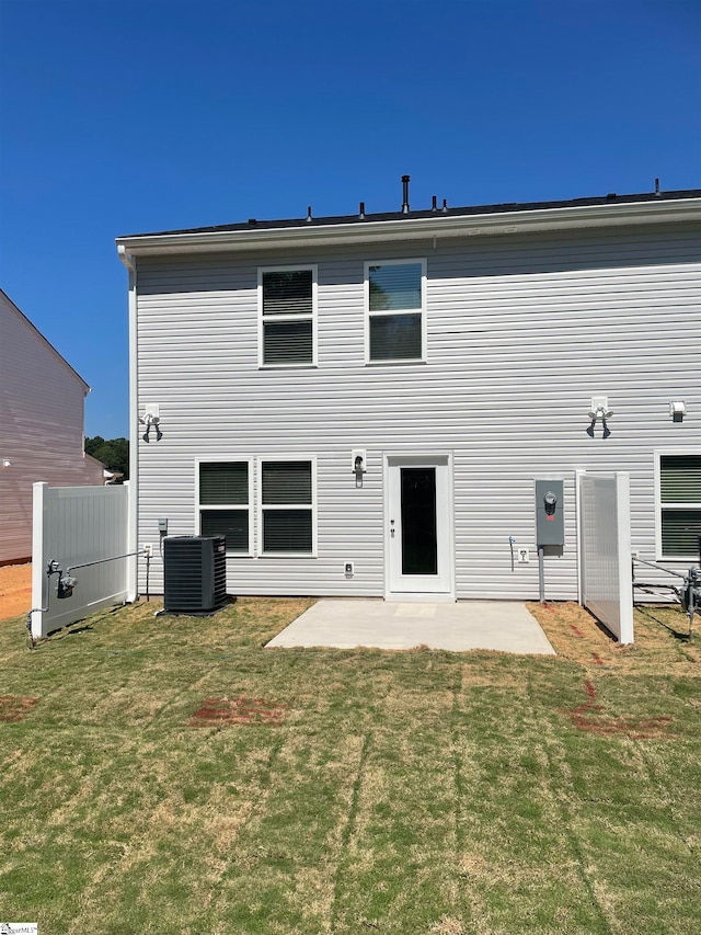 rear view of house with a patio, central AC, and a lawn