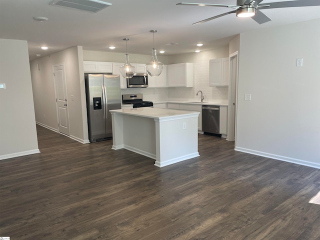 kitchen featuring pendant lighting, sink, appliances with stainless steel finishes, a center island, and white cabinets