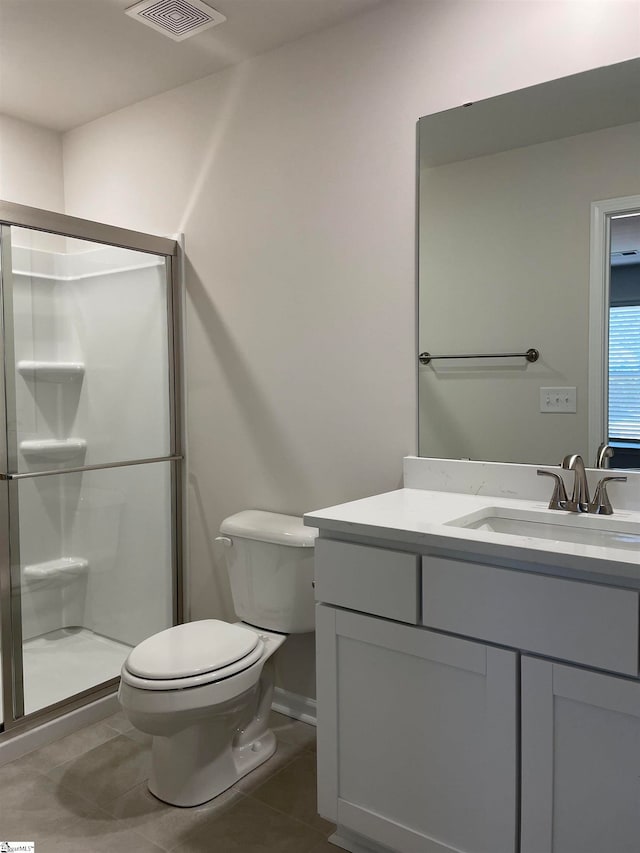 bathroom featuring a shower with door, vanity, tile patterned floors, and toilet