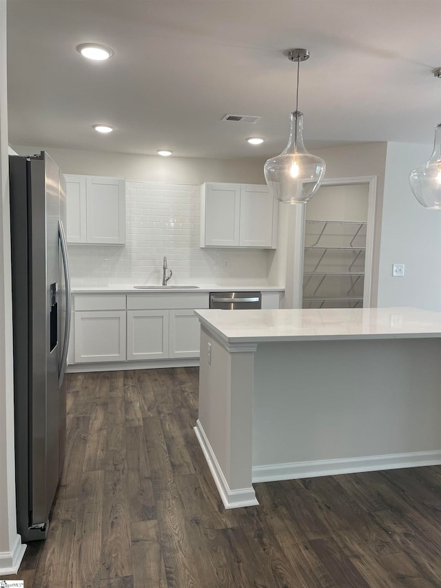 kitchen with stainless steel appliances, dark wood-type flooring, hanging light fixtures, white cabinets, and sink