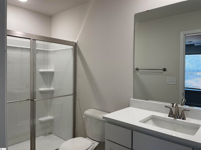 bathroom with a shower with shower door, toilet, and vanity