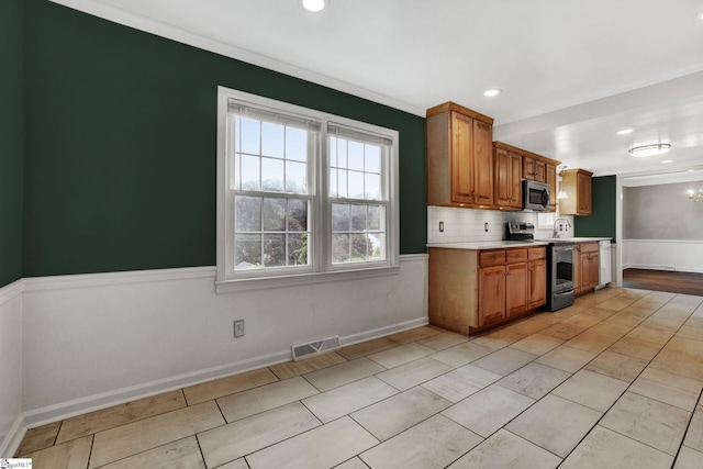 kitchen featuring stainless steel appliances, a sink, visible vents, light countertops, and brown cabinetry