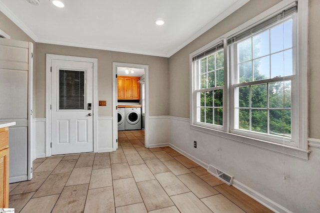 washroom with cabinets, ornamental molding, and washer and dryer