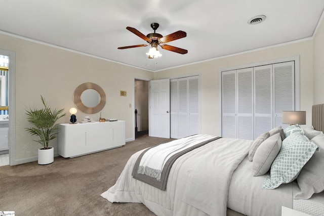 bedroom with ornamental molding, carpet, and two closets