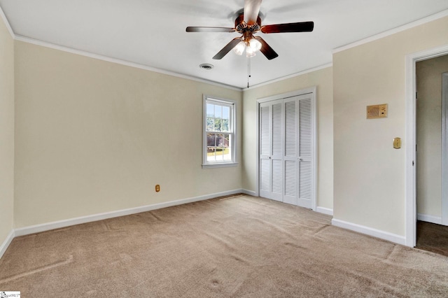 unfurnished bedroom featuring ornamental molding, carpet, ceiling fan, and a closet