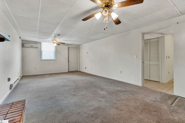 spare room featuring light carpet, a drop ceiling, a wall mounted air conditioner, and baseboards