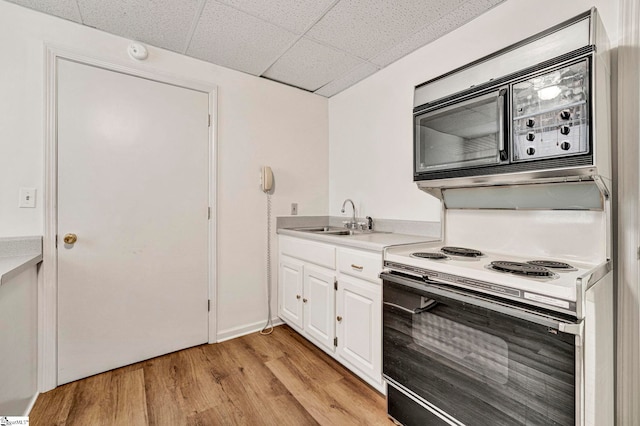 kitchen with light wood finished floors, white electric stove, light countertops, white cabinetry, and a sink