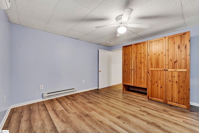 unfurnished room featuring a baseboard radiator, a paneled ceiling, light wood-style flooring, ceiling fan, and baseboards