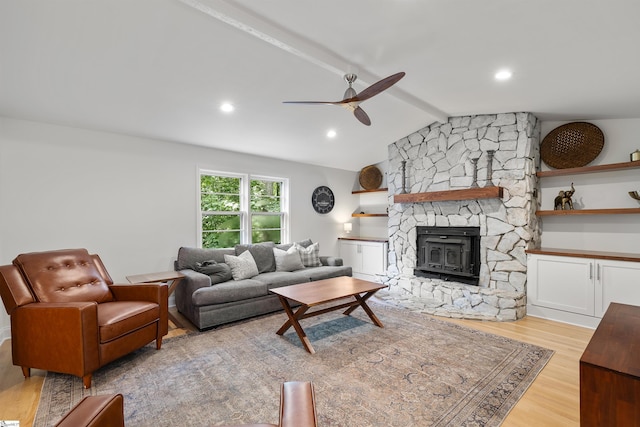 living room with a wood stove, ceiling fan, vaulted ceiling, and light wood-type flooring