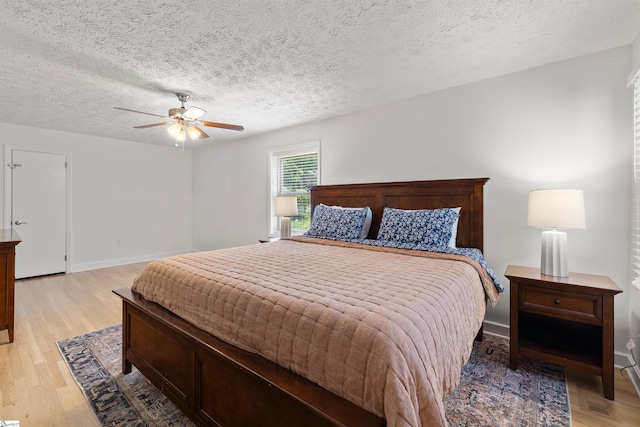 bedroom with ceiling fan, light hardwood / wood-style floors, and a textured ceiling