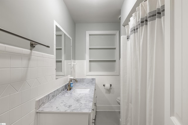 bathroom featuring vanity, toilet, and tile walls