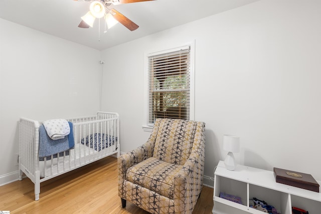 bedroom featuring hardwood / wood-style floors, ceiling fan, and a crib