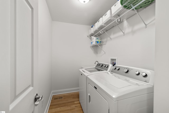 washroom with washer and clothes dryer and light wood-type flooring