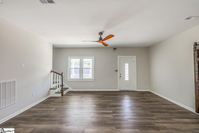 foyer featuring dark wood-type flooring, a barn door, and ceiling fan