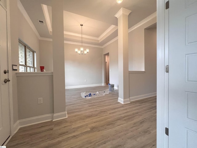 unfurnished room featuring baseboards, visible vents, a raised ceiling, wood finished floors, and a chandelier