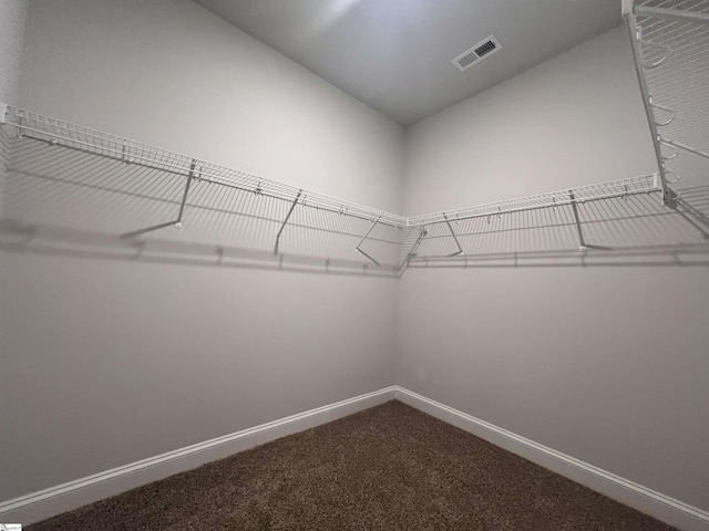 spacious closet featuring dark carpet and visible vents