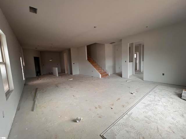 unfurnished living room featuring stairway