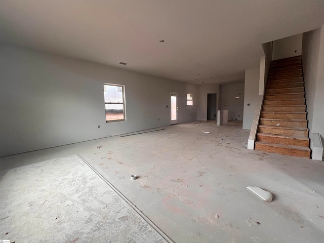 unfurnished living room featuring stairs