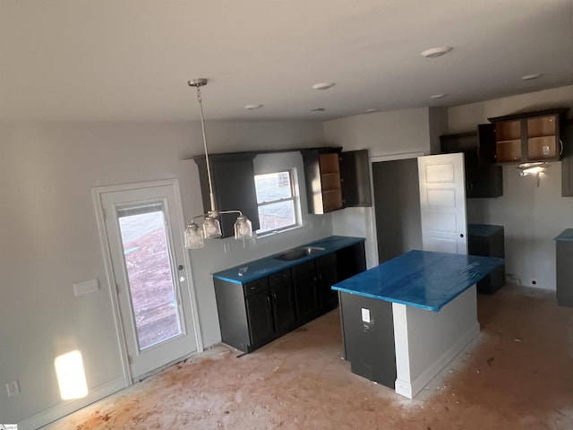 kitchen with a sink, dark countertops, a wealth of natural light, and a center island