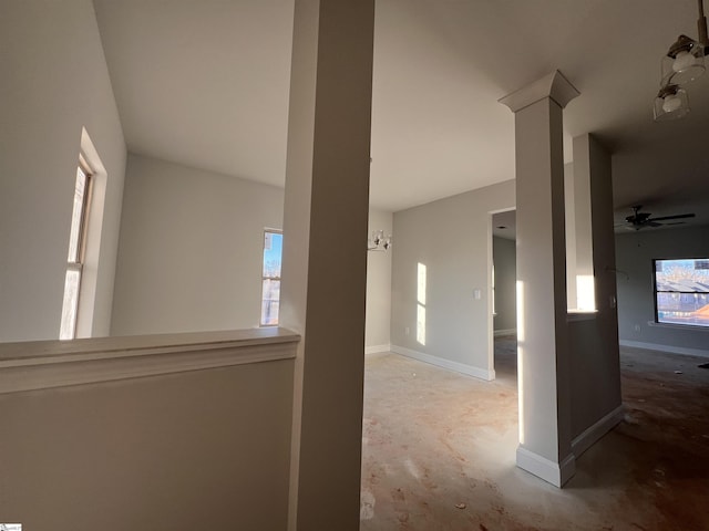 hallway with ornate columns, baseboards, and unfinished concrete flooring