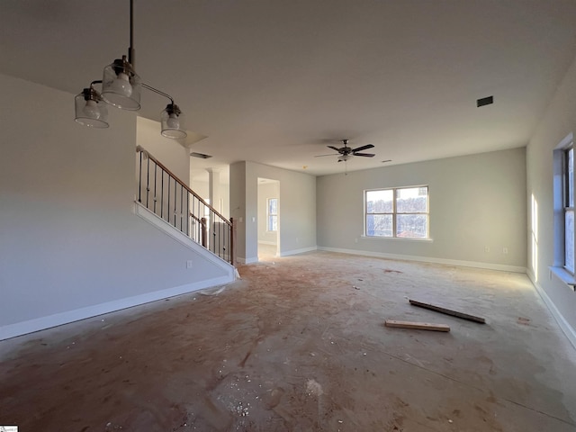 unfurnished living room with a ceiling fan, baseboards, and stairs