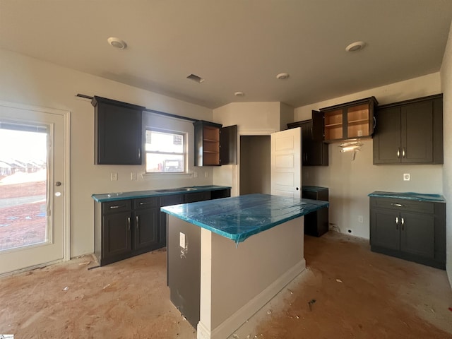 kitchen with open shelves, dark countertops, visible vents, and a center island