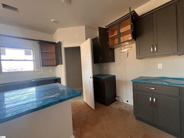 kitchen with unfinished concrete floors, dark countertops, and open shelves