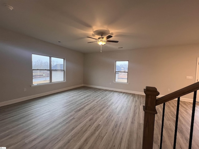 empty room featuring ceiling fan, baseboards, and wood finished floors