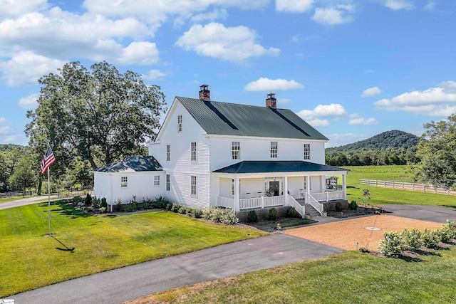 back of property with a porch, a yard, and a mountain view