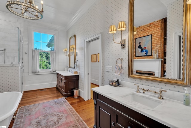 bathroom featuring vanity, hardwood / wood-style flooring, a chandelier, ornamental molding, and a washtub