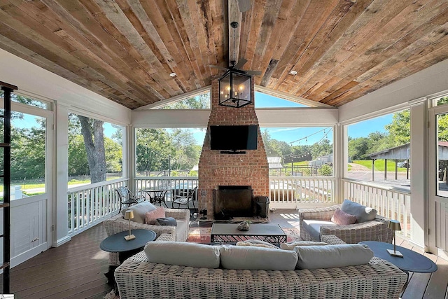 sunroom / solarium featuring lofted ceiling, a brick fireplace, wood ceiling, and ceiling fan