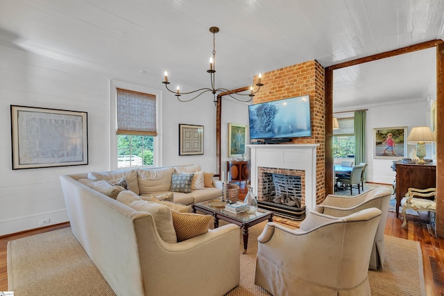 living room featuring a fireplace, a chandelier, wood-type flooring, and a healthy amount of sunlight