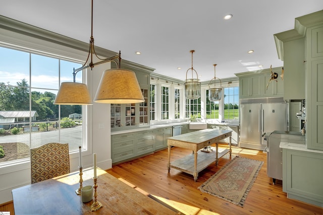 kitchen with pendant lighting, light hardwood / wood-style flooring, appliances with stainless steel finishes, and green cabinetry