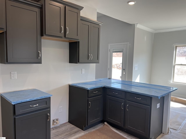 kitchen with ornamental molding, kitchen peninsula, and light hardwood / wood-style floors