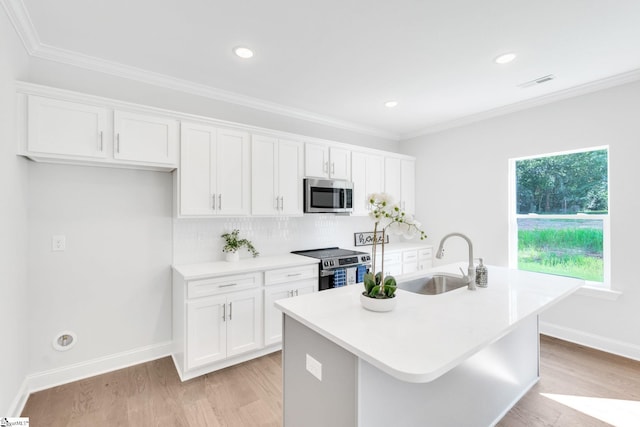 kitchen featuring decorative backsplash, appliances with stainless steel finishes, light wood-type flooring, and an island with sink