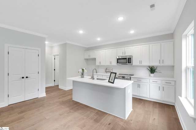 kitchen featuring white cabinets, light hardwood / wood-style floors, appliances with stainless steel finishes, and a center island with sink