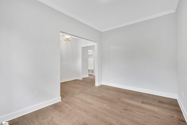 unfurnished room with ornamental molding, a notable chandelier, and light wood-type flooring